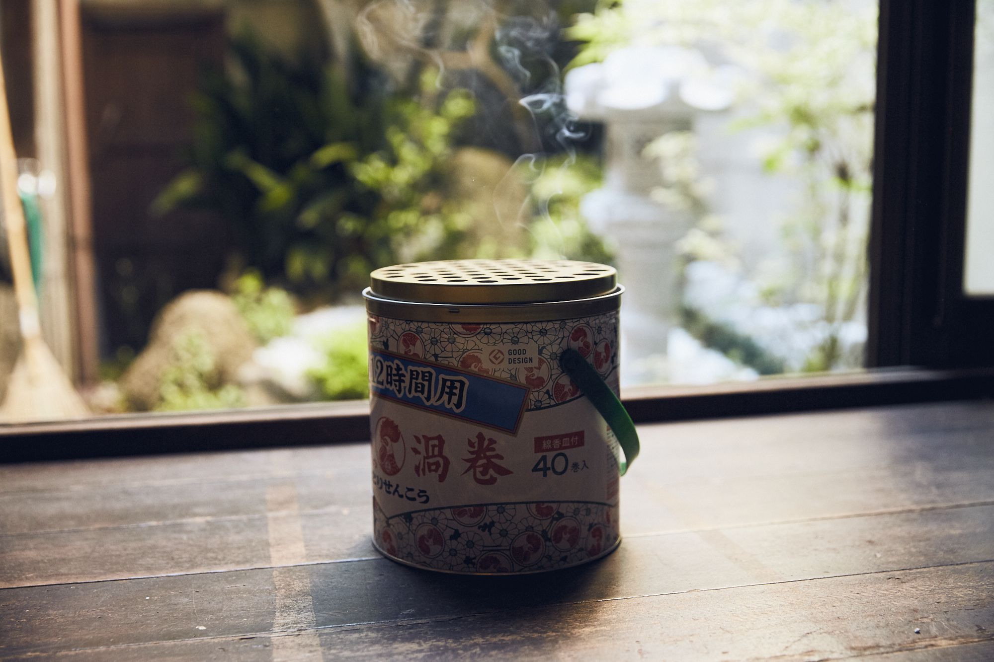 A canister with Japanese text on a wooden surface near a window.