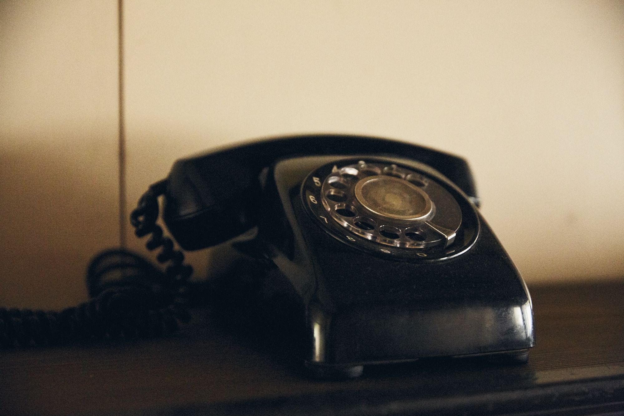 Un teléfono antiguo con disco giratorio sobre un escritorio.