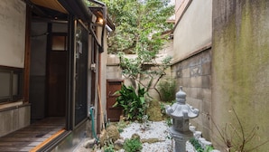 Un jardín japonés tradicional con un farol de piedra, una puerta de madera y un pequeño árbol.