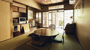 Una habitación tradicional japonesa con suelo de tatami, una mesa baja y una puerta corredera que da a un jardín.