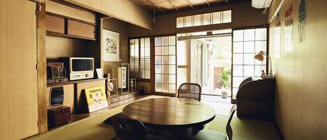 A traditional Japanese room with tatami flooring, a low table, and a sliding door leading to a garden.