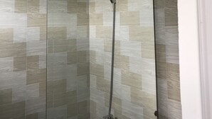 Une douche équipée d’un pommeau de douche à main et d’un robinet fixé au mur.