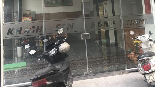 L’entrée d’un hôtel, avec l’inscription « HOTEL HÒNG THÌNH » bien visible.