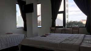 Une chambre d’hôtel avec deux lits, un téléviseur fixé au mur, une petite table et une chaise.
