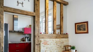 A kitchen with red cabinets, a wooden beam, and a stone wall.