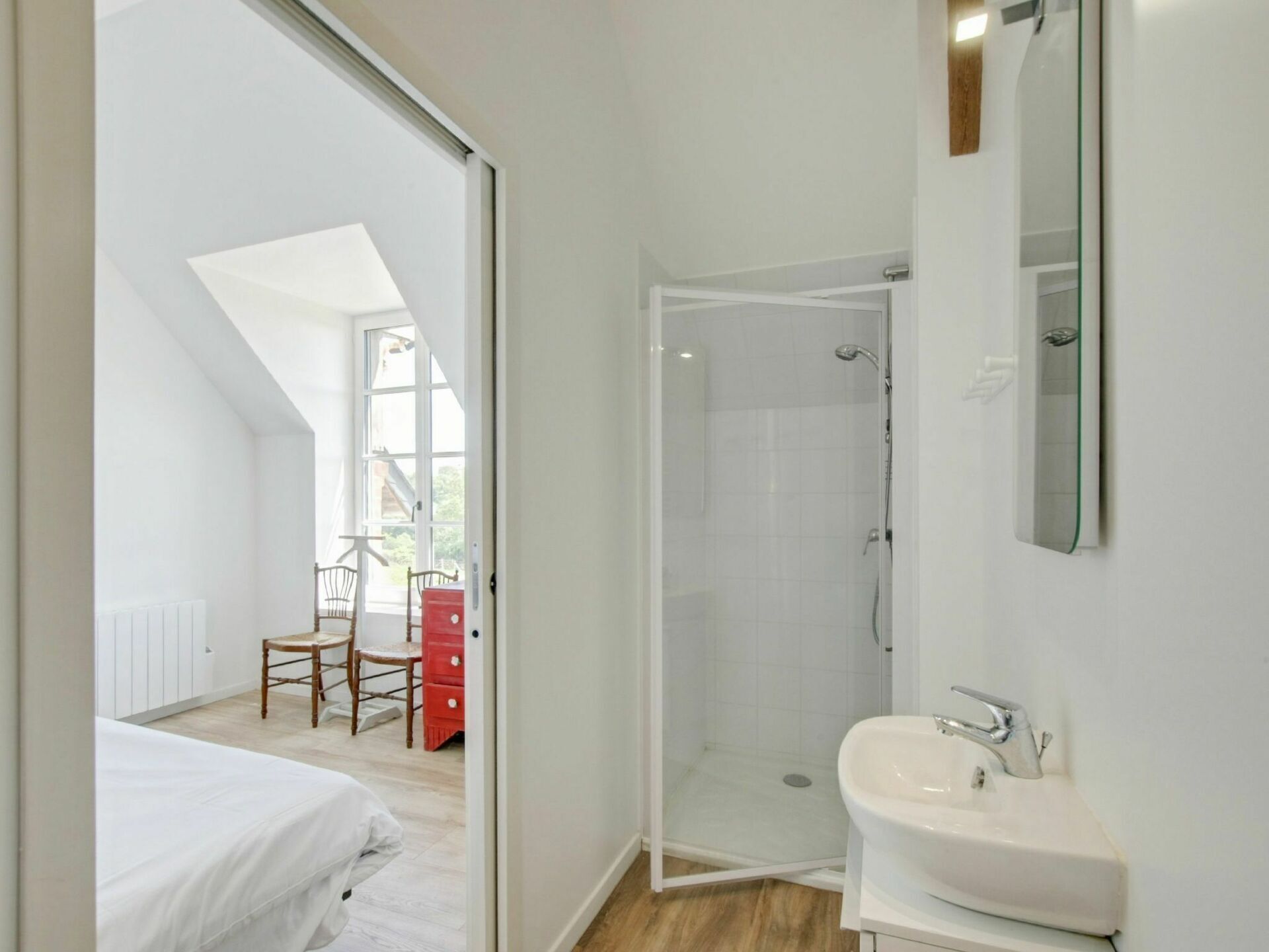 Un baño moderno con ducha, lavamanos y un espejo grande.