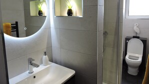 A modern bathroom with a large mirror, a sink, a toilet, and a shower area.