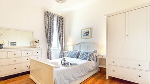 A bedroom with a bed, bedside tables, a wardrobe, and a mirror.