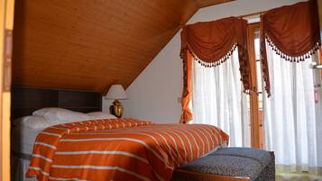 Un dormitorio con cama, mesita de noche, lámpara y ventana con cortinas.