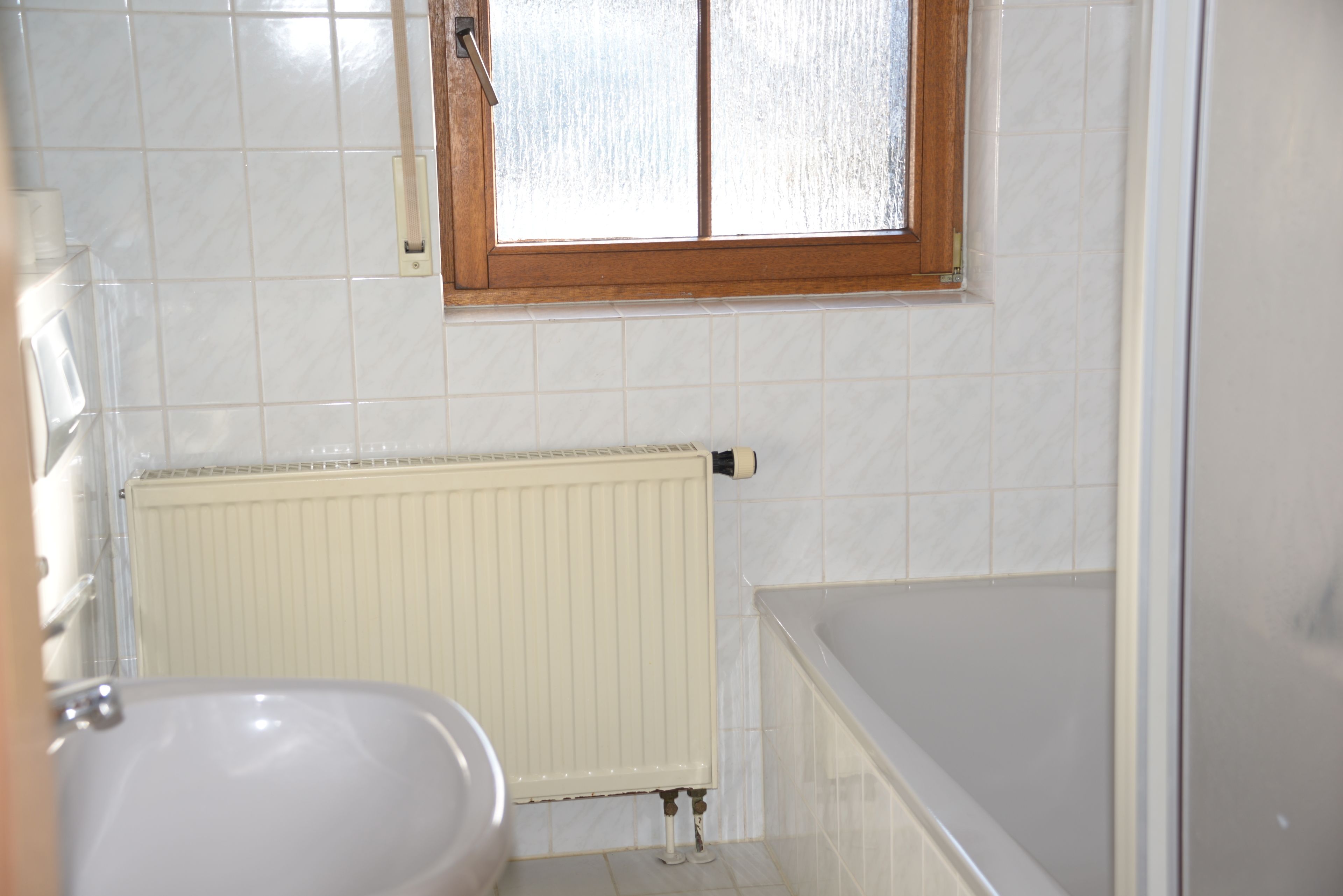 Une salle de bain avec une baignoire, des toilettes et une fenêtre.