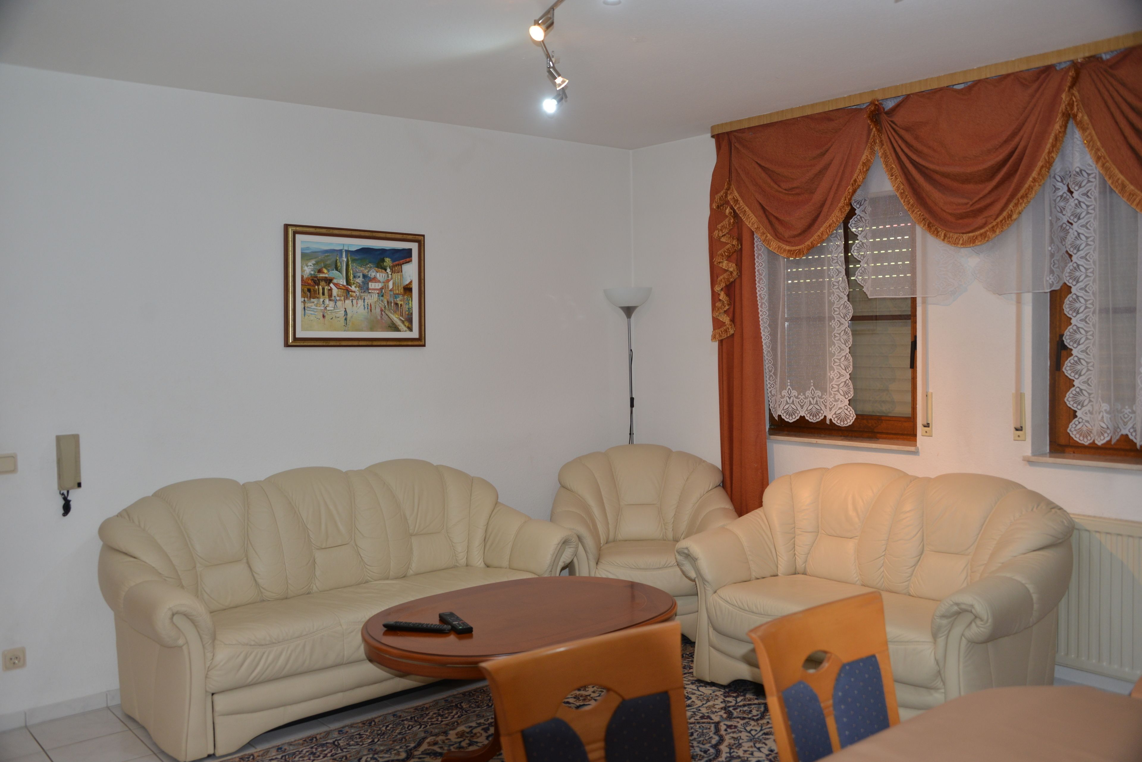 Un salón con dos sofás color beige, una mesa de centro de madera y una alfombra estampada.