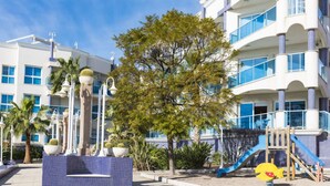 A modern building with multiple balconies, a children's play area, and a decorative fountain. - Beautiful apartment for 4 people with pool, A/C, WIFI, TV and balcony (Ulldecona)