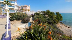A coastal hotel with balconies overlooking the sea, a landscaped garden with tropical plants, and a clear blue sky. - Beautiful apartment for 4 people with pool, A/C, WIFI, TV and balcony (Ulldecona)