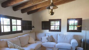Una sala de estar acogedora con un sofá blanco, una mesa de centro de madera y una lámpara colgante.