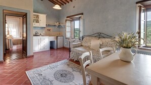 A cozy room with a bed, a dining table, and a kitchen area. - Apartment overlooking the Sienese hills, swimming pool and free wi-fi (Casole d'Elsa)