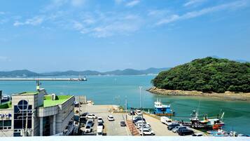 A coastal area with a parking lot, a bridge in the background, and a forested island.