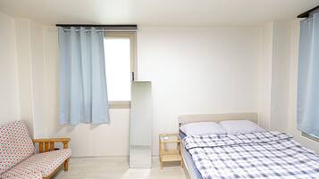 A bedroom with a bed, a small bedside table, a nightstand, a bench, and a mirror.