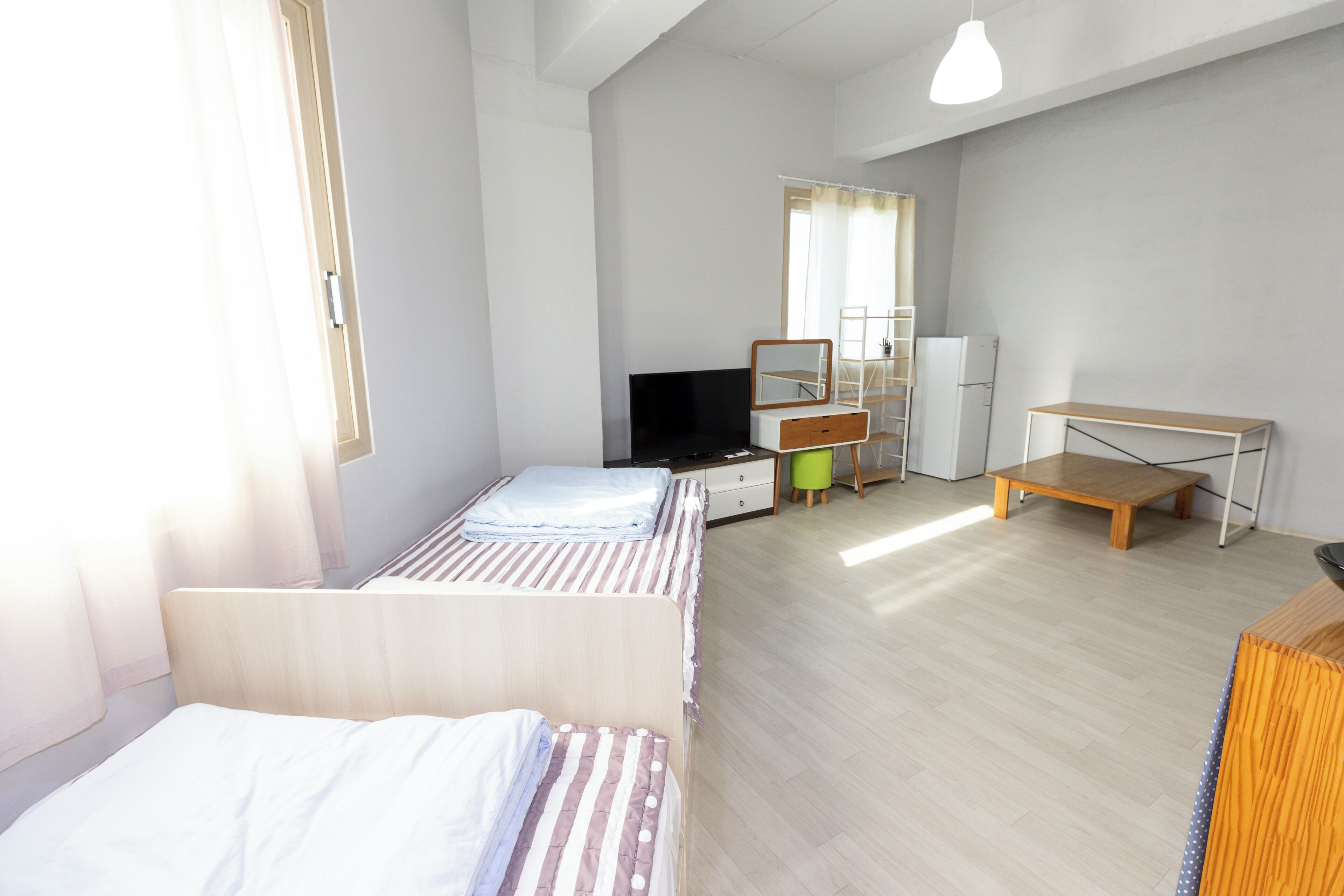 Una habitación con dos camas, un escritorio, un espejo y un televisor.