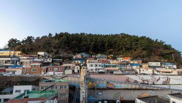 A residential area with houses on a hillside, a parking lot, and a mural on a building.
