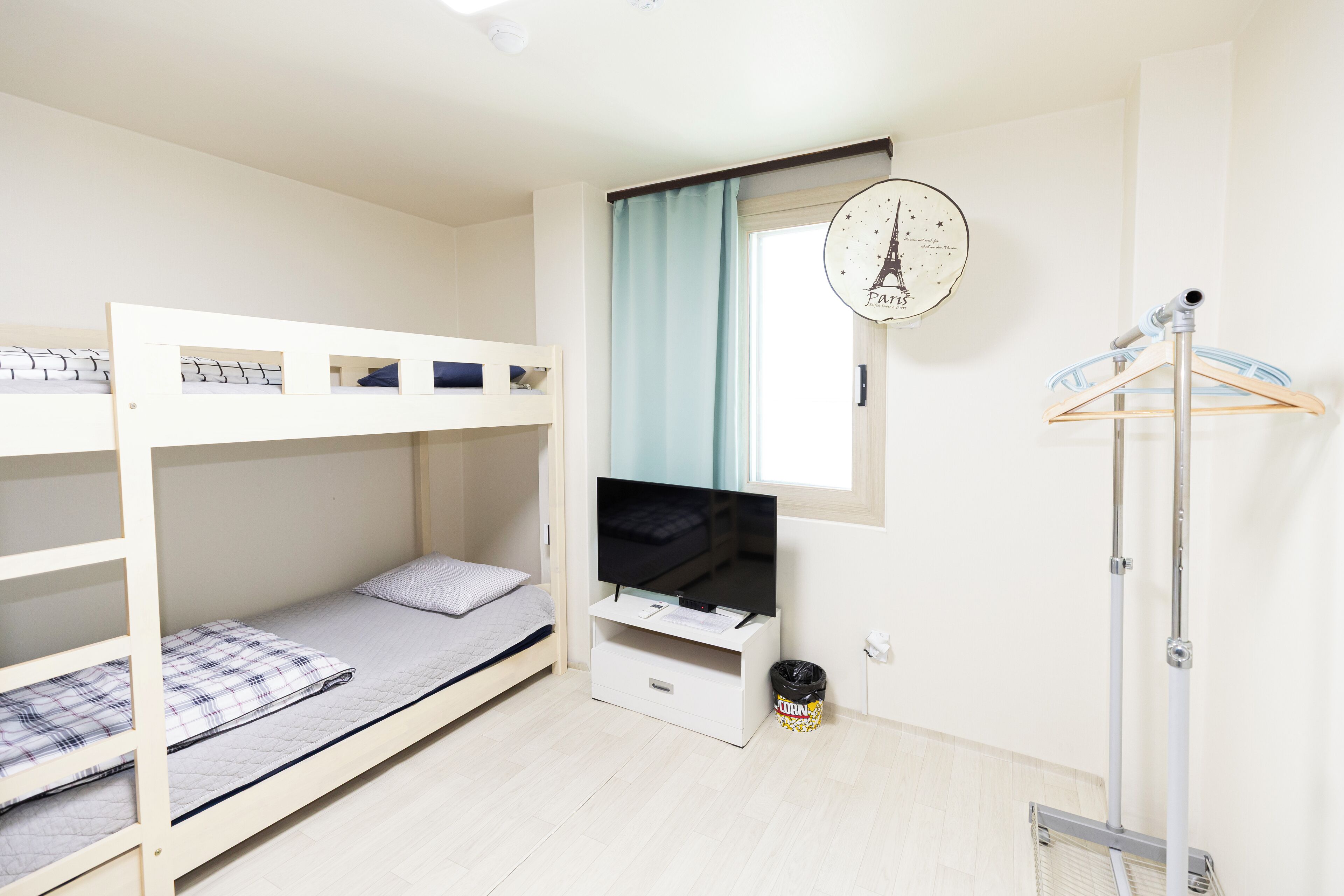 A bunk bed room with a TV, a small desk, and a coat rack.