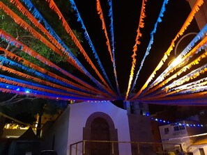 Streamers converge towards a central point, suspended between two structures with an arched doorway.
