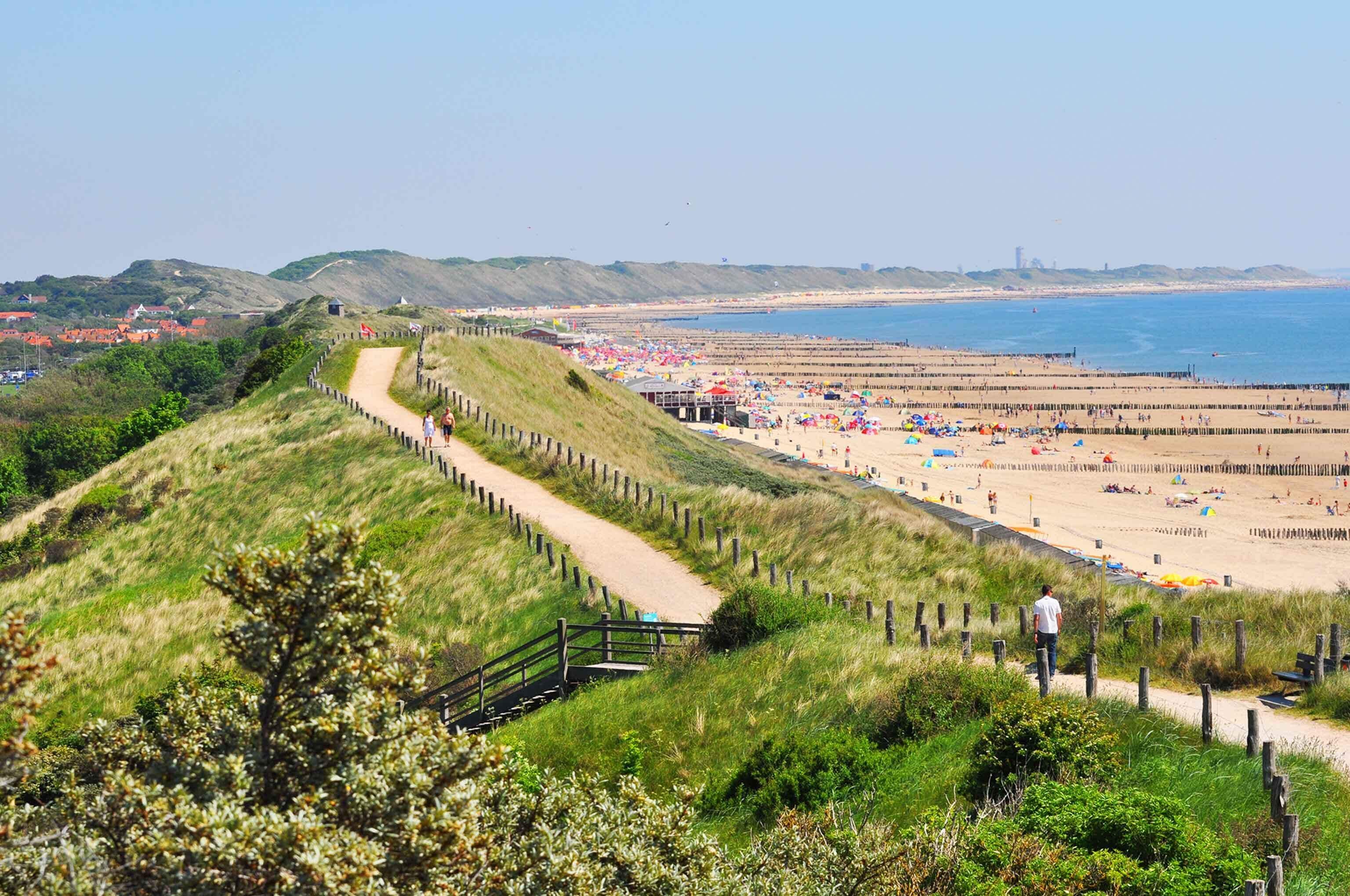 Un paysage côtier avec une plage de sable, une promenade en bois et une vue dégagée sur la mer.