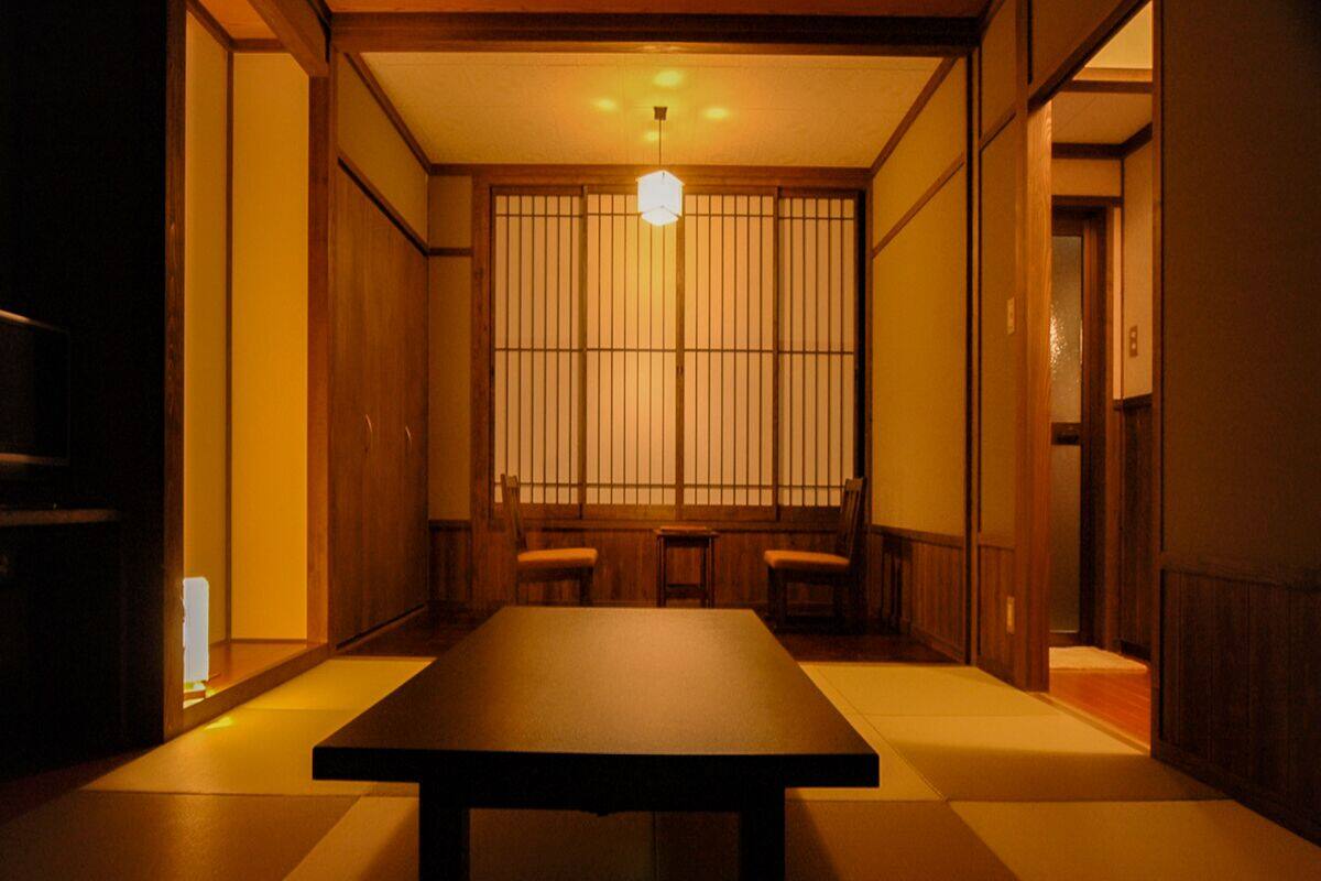 Une pièce de style japonais traditionnel, avec un sol recouvert de tatamis, une table basse et des portes coulissantes.
