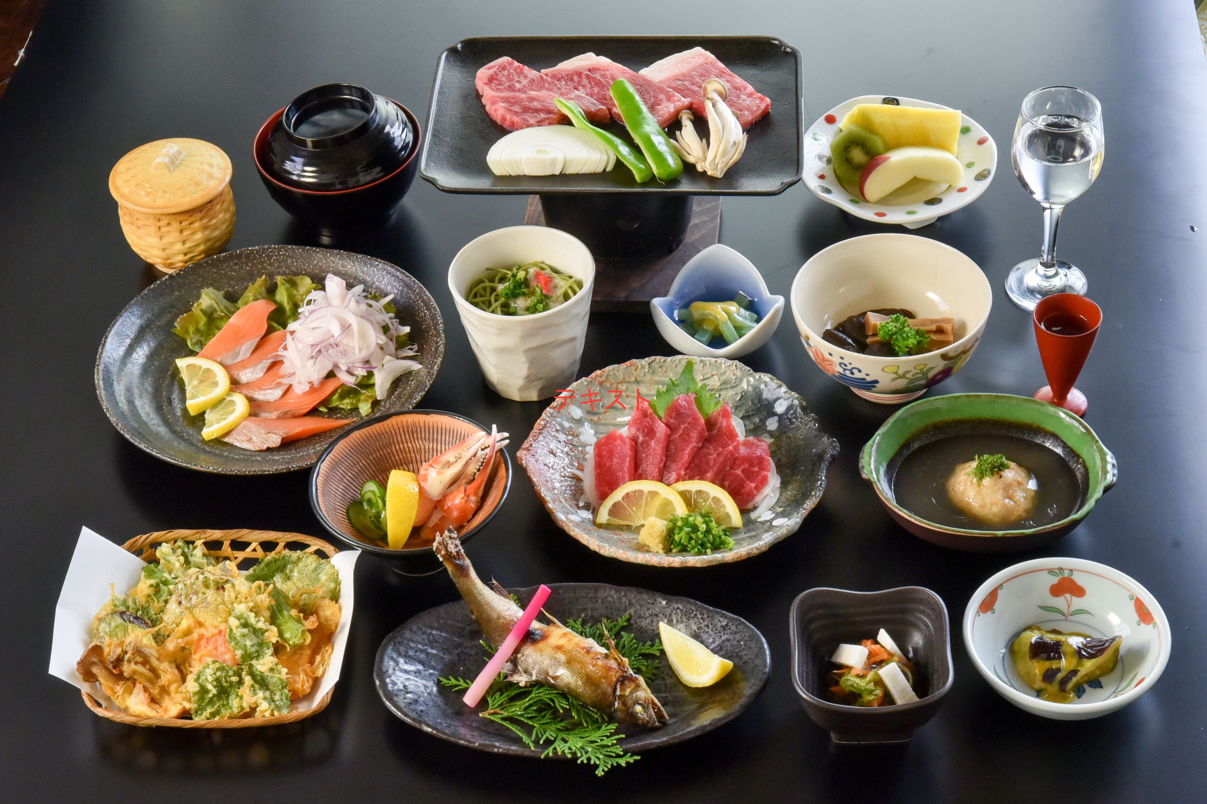 Variedad de platos japoneses, como sashimi, sushi y tempura, sobre una mesa.