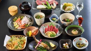 Variedad de platos japoneses, como sashimi, sushi y tempura, sobre una mesa.