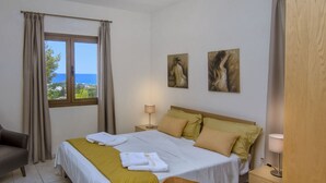 A hotel room with a bed, a chair, a nightstand, and two paintings on the wall. - Superb Villa in Coral Bay Paphos, with Half Cost of the HEATED POOL Nov-Mar 26 (Paphos (Pafos))