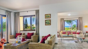 A spacious living area with wicker furniture, a glass coffee table, and a view of the outdoors. - Superb Villa in Coral Bay Paphos, with Half Cost of the HEATED POOL Nov-Mar 26 (Paphos (Pafos))