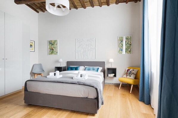 A modern bedroom with a bed, bedside tables, a chair, and artwork on the walls. - Grotta Pinta Apartment - Int. 13 (Roma)