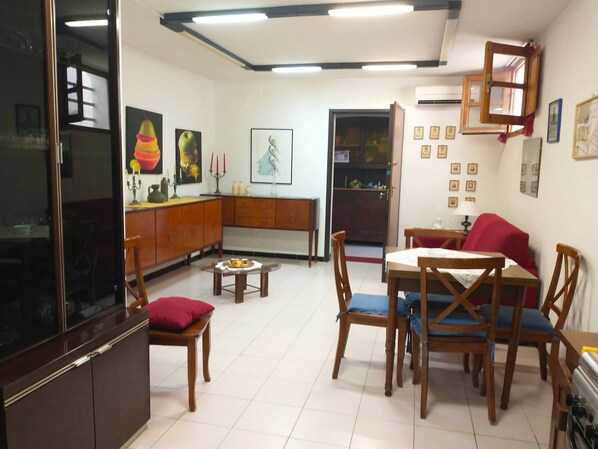 A living room with a dining area, wooden furniture, a TV, and wall-mounted decorations.