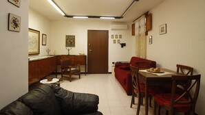 Un espai habitable compacte amb zona de menjador, sofà i un canapè vermell.