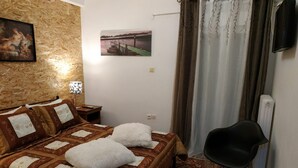 A bedroom with a bed, a chair, a picture on the wall, and a window with curtains. - Sweet Home Apartment in the center of the city (Korinthos)