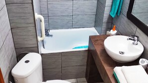 A compact bathroom with a toilet, bathtub, and sink. - Sweet Home Apartment in the center of the city (Korinthos)