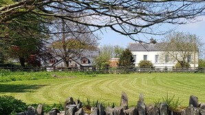 A large, white house with multiple windows and a well-maintained lawn in the foreground.