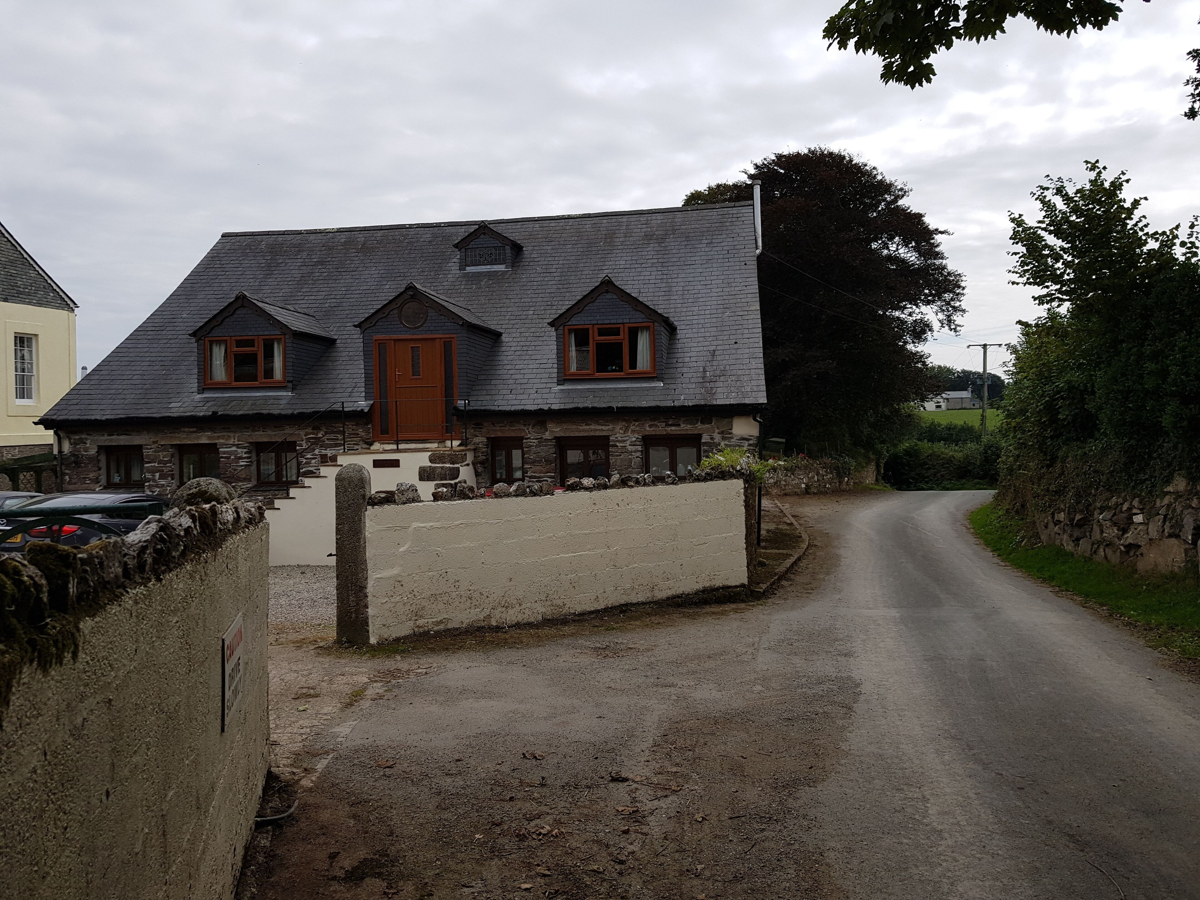 Une maison en pierre à deux étages, avec un toit en pente et une porte en bois.