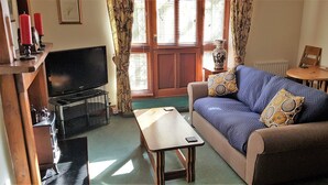 A living room with a sofa, a coffee table, a TV, and a chair.