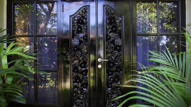 Uma porta preta com detalhados entalhes florais e uma fechadura.