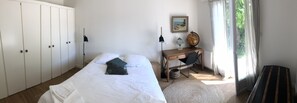 Ein Schlafzimmer mit einem Bett, einem Schreibtisch, einem Globus und einem Bild an der Wand.