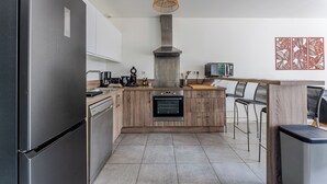 A modern kitchen with a stainless steel refrigerator, built-in oven, and wooden cabinetry. - Beautiful wooden house with terrace and large garden - Bassin d'Arcachon (Arès)