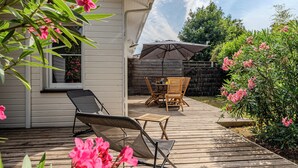 A wooden deck with outdoor furniture, a patio umbrella, and flowering plants. - Beautiful wooden house with terrace and large garden - Bassin d'Arcachon (Arès)