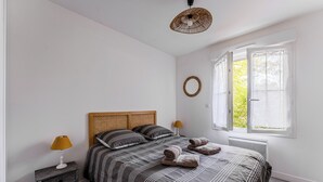 A bedroom with a bed, bedside lamps, a window, and a wall-mounted light fixture. - Beautiful wooden house with terrace and large garden - Bassin d'Arcachon (Arès)
