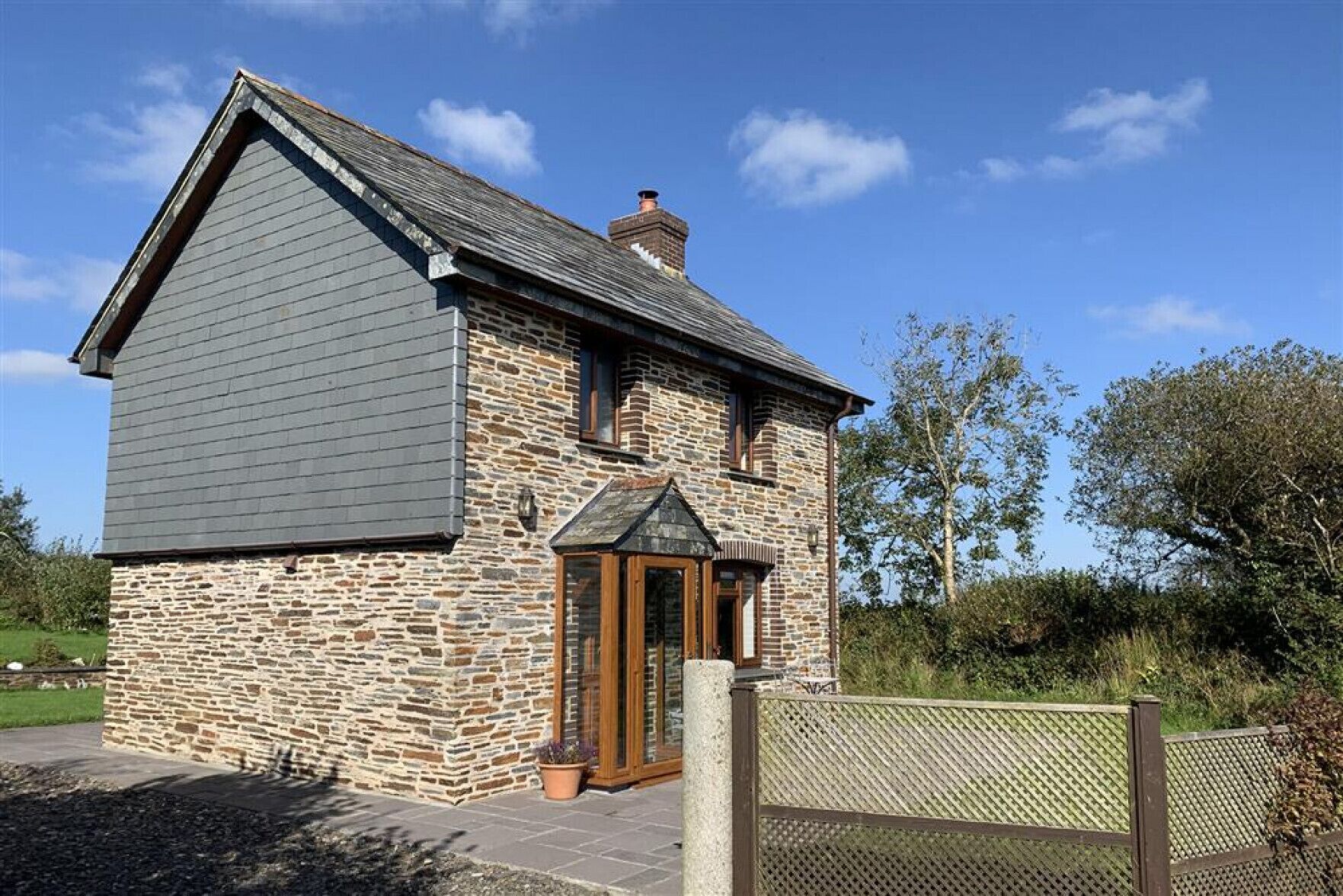 A stone house with a grey roof, a wooden door, and a small porch.