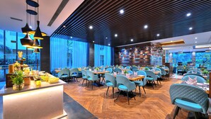 Un restaurant moderne doté d’une grande salle à manger, de chaises bleues rembourrées et d’un buffet situé sur le côté gauche.