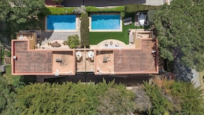 Ein zweistöckiges Haus mit Dachterrasse, Swimmingpool und Garten.