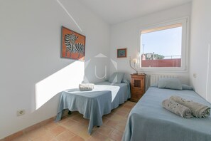 A bedroom with two beds, a small table, and a window with a view. - Private villa with pool in Calella, 7min-walk to beach (Palafrugell)