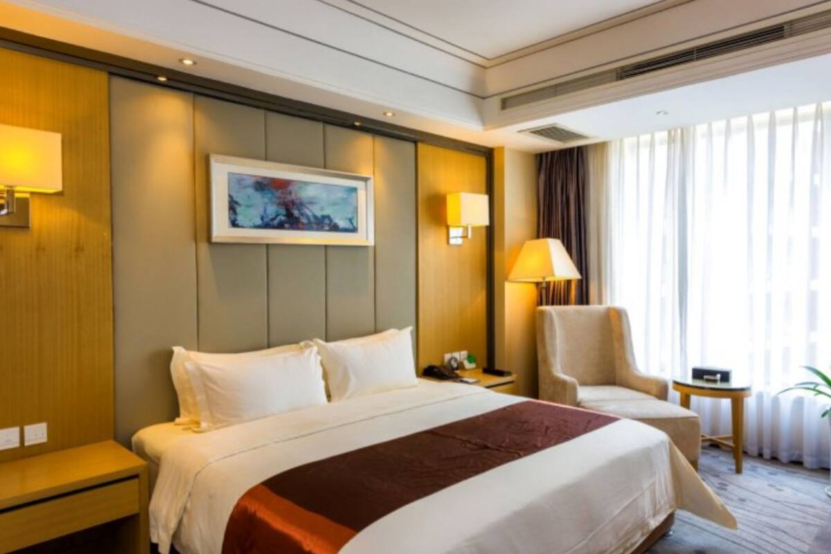 Ein Hotelzimmer mit einem großen Bett, einem Sessel, einem kleinen Tisch und einem Bild an der Wand.