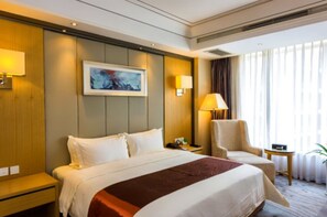 A hotel room with a large bed, a chair, a small table, and a painting on the wall. - Xiedu Hangchen International Hotel (Chengdu)